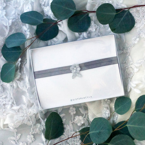Silver Toss Garter In Gift Box With Eucaluptus Surrounding on Lace Wedding Background