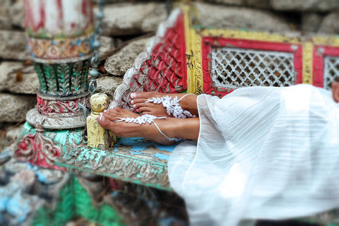 Off-White Barefoot Sandals on Bride's Bare Feet Up On A Colorful Bench with a White Flowy Skirt